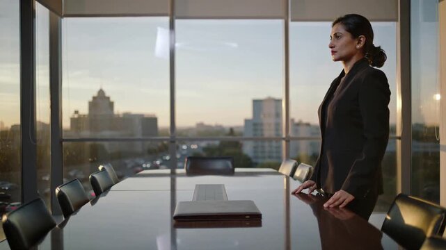 Preparing meeting, exec in suit placing folio on conference table, standing viewing city