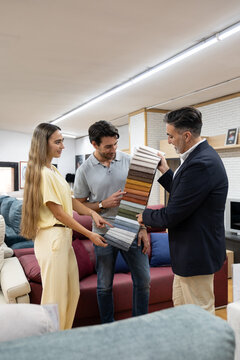 Couple selecting fabric swatches for new sofa with assistance from a salesman