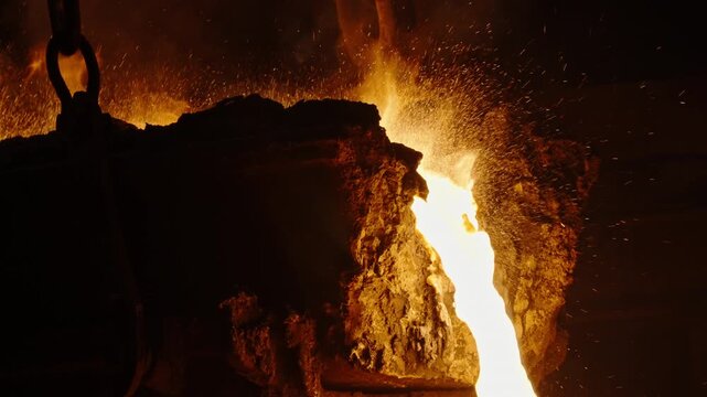 Molten Metal Pouring from Furnace with Sparks in Industrial Foundry