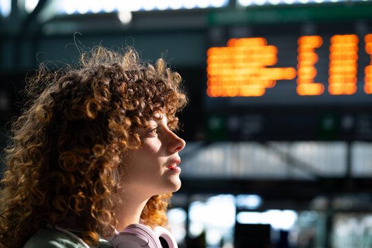White woman with curly hair wearing headphones waiting