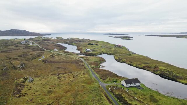 Sweeping aerial drone view across Grimsay near North Uist in the Outer Hebrides, Scotland, showing remote homes, winding roads, tidal coastal water and rugged island landscape
