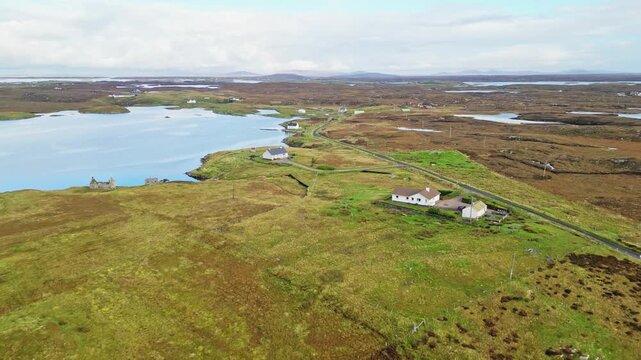 Grimsay near North Uist in the Outer Hebrides, Scotland, showing remote homes, winding roads, tidal coastal water and rugged island landscape, cinematic aerial reveal view