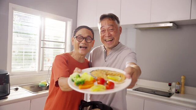 Happy Asian senior gay man couple preparing and enjoying healthy organic dinner together in kitchen at home, cooking fresh vegetables and sharing wellness routine for active retirement lifestyle.