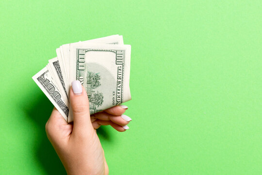 Top view of female hand holding a pack of money on colorful background. One hundred dollars. Business concept with empty space for your design. Charity and tips concept