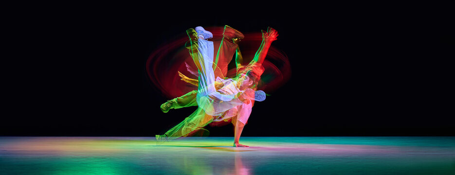 Street dancer captured during low sweeping footwork with colorful motion trails. Concept of dance event posters, music media, youth culture ads and festival visuals.