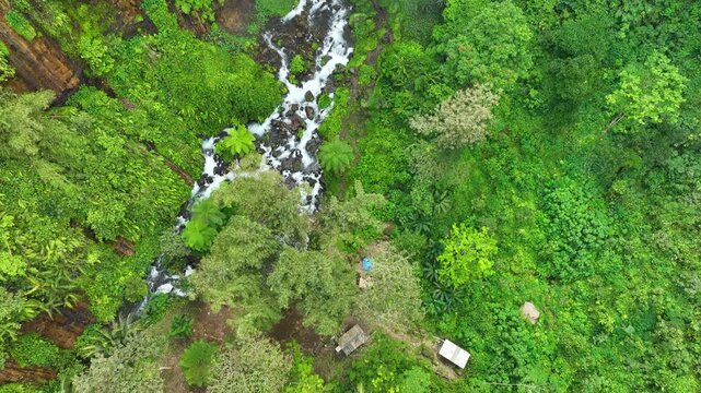 Aerial Tilt Up Revealing Kapas Biru Waterfall in Tropical Forest Landscape, East Java Indonesia