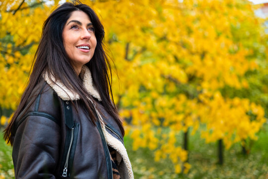 Beautiful young woman with leather jacket smiling  in the autumn park 
