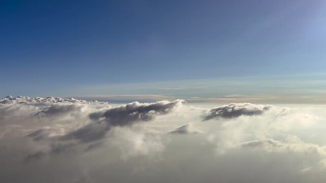 An immersive pilot&rsquo;s perspective taken from. a jet cockpit, flying over a layer of ethereal broken stratus clouds bathed in the soft siunrise nlight, with the sun shining in the upper right.corner