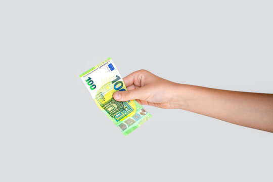 Hand holding a 100 euro bill. Man hand is holding a 100 Euro bill. Money, cash. Hand taking a banknote of 100 euro. Woman's hand holding one hundred euro banknote. Isolated on gray