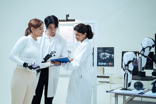 A group of researchers examines a robotic prosthetic limb in a modern laboratory, testing coordination and discussing data from a clipboard to advance biomedical engineering and innovation.