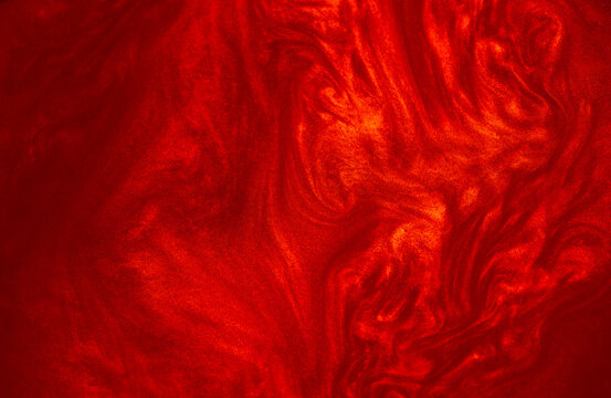 Shimmering red abstract background. Liquid glitter paint texture waves and swirls. Beautiful shiny red glitter texture. Metallic paint close-up as a holiday background.