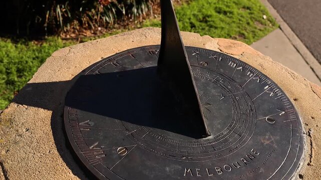 Close up of old sundial casting a moving shadow on numbered face showing time outdoors.