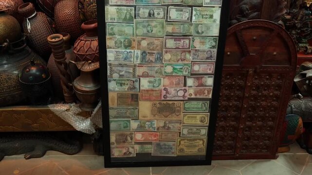 A captivating display of international paper money framed and showcased amidst a collection of cultural artifacts and antiquities.
