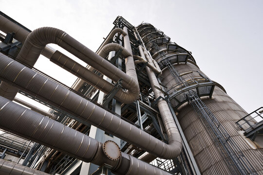 Distillation column rising beside a run of insulated process pipe
