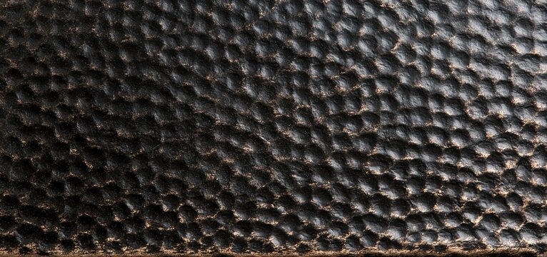 Industrial-style hammered metal tile in black and bronze with a matte finish and warm highlights.