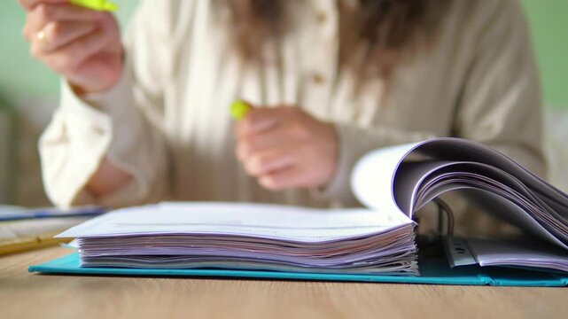 Close Up of Hand Highlighting Text in Thick Document Folder with Yellow Marker Pen, Audit and Study Concept