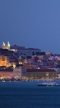 View of Lisbon over Tagus river with passing ferry boat from Almada with ferry in evening twilight. Lisbon, Portugal