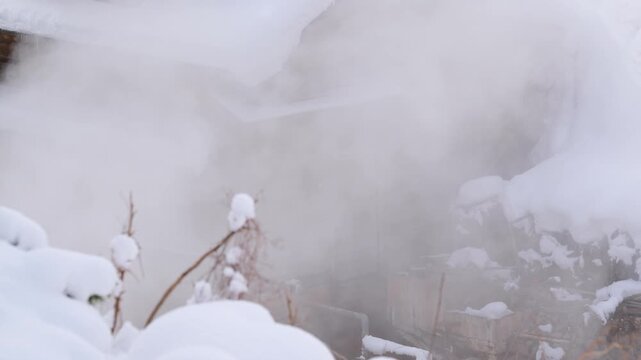 深い雪に覆われた山間のレトロな木造温泉宿と立ち上る湯気のスローモーション