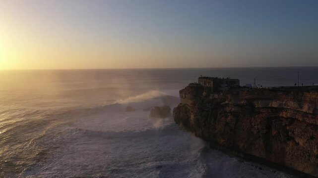 Nazar&eacute; Cliff with giant waves at sunset
