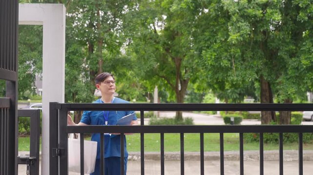 Asian male professional caregiver or nurse ringing doorbell at senior patient home for home visit, arriving to check on elderly person, home healthcare, medical support and in home care service.