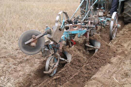 A Vintage Farming Plough Cutting a Deep Furrow.