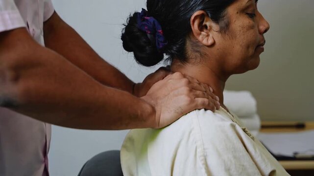 Placing hands at skull base masseur applying neck-shoulder massage clinic seeking relief with towel
