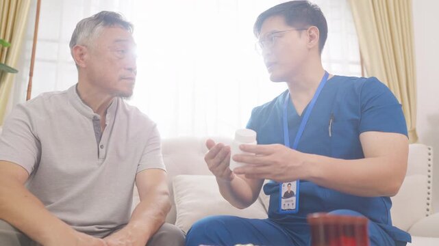 Male caregiver showing medication to senior man patient at home, elderly healthcare support, medicine and treatment consultation, home care nursing service and aging society lifestyle concept