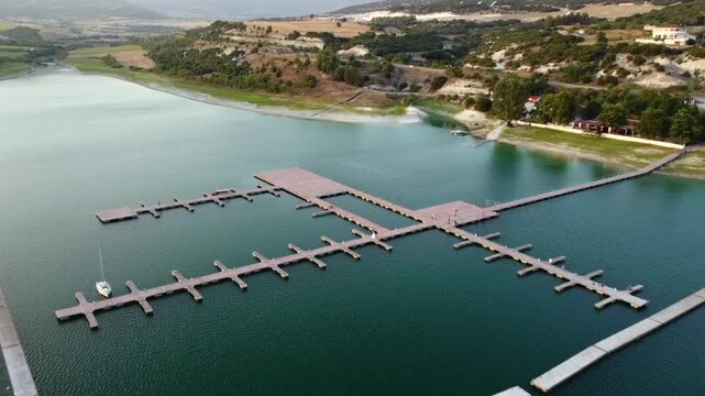 High angle panoramic drone shot capturing the scenic waters of Polyfytos Lake reservoir and the Nautical Club pier near Servia.
