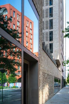 Pedestrian walkway between contemporary building facades and greenery, showing access, circulation and everyday movement through a modern urban setting
