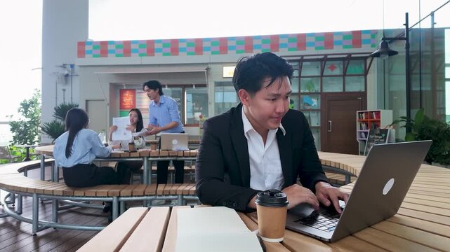 Smiling Asian Businessman Working on Laptop at Outdoor Office in Bangkok