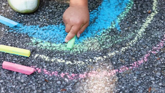 Close-up 4K footage of a child's hand coloring a rainbow. The vibrant crayons and focused gesture illuminate the beauty of youthful imagination. Slow motion video.