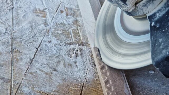 The process of cutting or grinding tiles with an angle grinder at a construction site. Close-up of a rotating diamond disc of a grinder, dust formation during construction and repair work.
