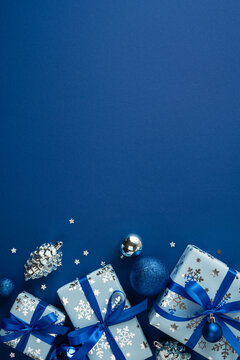 Blue Christmas presents with ribbons and ornaments for Merry Christmas and Happy New Year on vertical navy blue copyspace