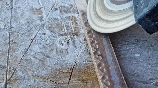 The process of cutting or grinding tiles with an angle grinder at a construction site. Close-up of a rotating diamond disc of a grinder, dust formation during construction and repair work.