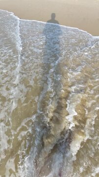 La silhouette d'une ombre qui marche sur la plage et dans les vagues