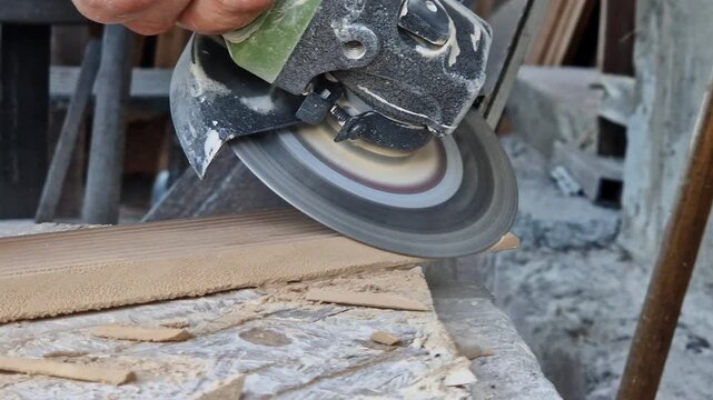 The process of cutting or grinding tiles with an angle grinder at a construction site. Close-up of a rotating diamond disc of a grinder, dust formation during construction and repair work.