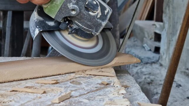 The process of cutting or grinding tiles with an angle grinder at a construction site. Close-up of a rotating diamond disc of a grinder, dust formation during construction and repair work.