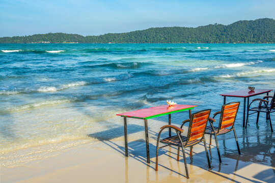 Colrful chairs and table on the the beach in the water, seaside bar and restaurant on the island of Koh Rong Sanloem, Cambodia