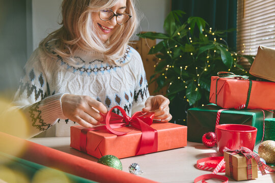 Woman wrapping Christmas gifts at home.
Preparing presents for loved ones reflects holiday shopping, seasonal celebrations, gift giving and the joy of Christmas traditions.