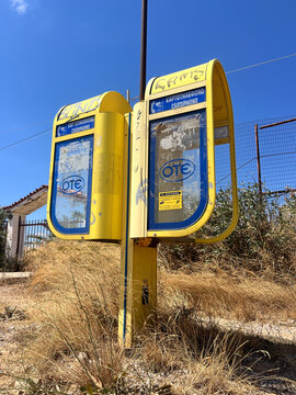 SPATA, GRECIA - 16 AGOSTO 2026: Telefoni pubblici gialli a pagamento della compagnia nazionale di telecomunicazioni OTE su un marciapiede, un cimelio nostalgico di tecnologia vintage.