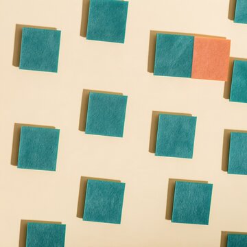Large orange felt square emerging from a pattern of teal tiles on a pale yellow background, a clean mockup for streaming services