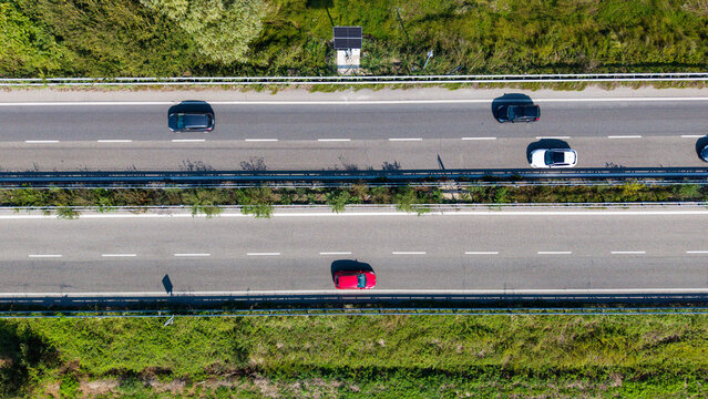 Highway Traffic from Above: An aerial view captures a busy highway with several cars driving in multiple lanes, surrounded by green vegetation on the sides.