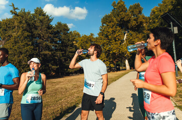 Obraz premium Runners taking a break to drinking water during marathon event.