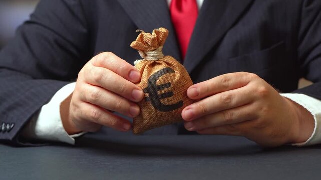 Businessman holds euro money bag in his hands. Banking and crediting. Mortgage, loan approval. Salary benefits. Attracting investments. Deposit savings. Cashback.