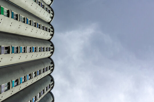 Vertical view of concrete cylindrical silos converted to student housing in Gr&uuml;nerl&oslash;kka, Oslo, with small colorful glass windows against an overcast sky