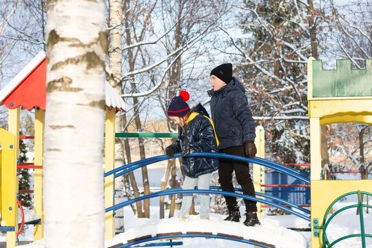 Children playing on a snow-covered playground bridge, enjoying a winter day.