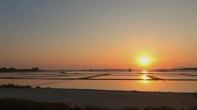 Golden sunset over tranquil salt pans near Trapani, Italy
