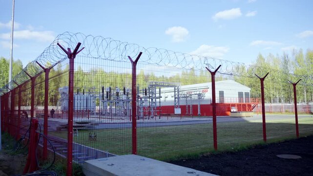 Critical infrastructure facility occupies fenced territory. Protective barrier and dense strands of barbed wire surround technical area