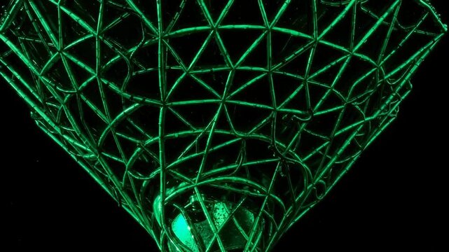 Glowing green wireframe funnel or inverted geometric mesh forming a symmetrical abstract vortex against a deep black background
