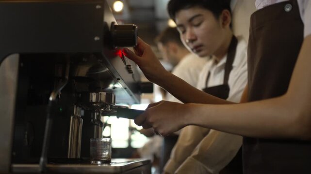 Teenage barista trainee learns to operate espresso machine in cafe